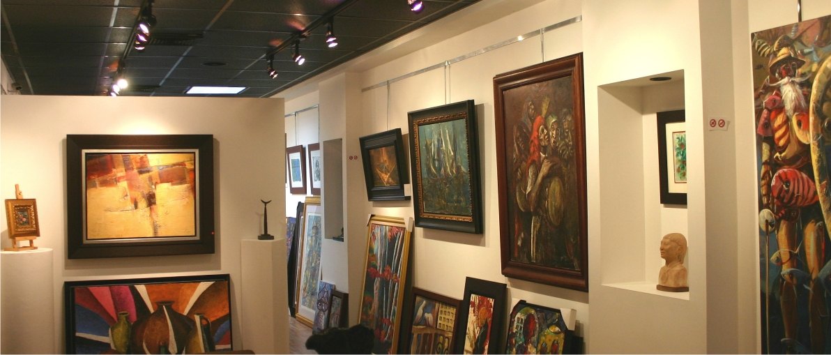Sala de la galería con pinturas enmarcadas, una escultura y un cuadro grande de un músico